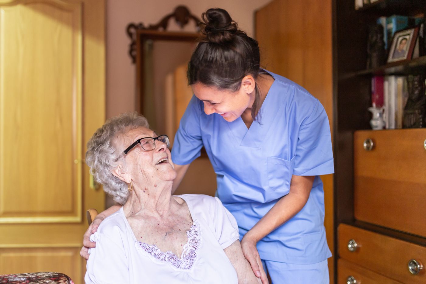 Happy senior woman laughing with her caregiver home